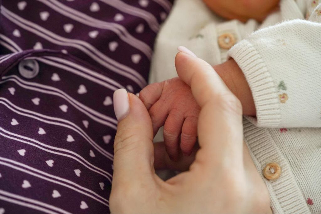 Handje van een pasgeboren baby in de hand van haar moeder